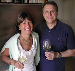 Weinliebhaber-Paar mit Weingläsern, lächelt in die Kamera