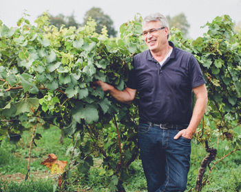 Winzer im Weinberg, glücklich und lächelnd