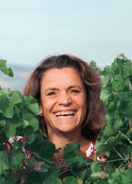 Winzerin lächelt vor Weinreben im Weinberg