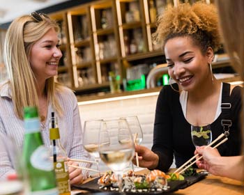 Freundinnen genießen Wein und Sushi im Restaurant