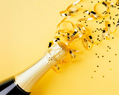 Sektflasche gelber Hintergrund Konfetti jubiläum