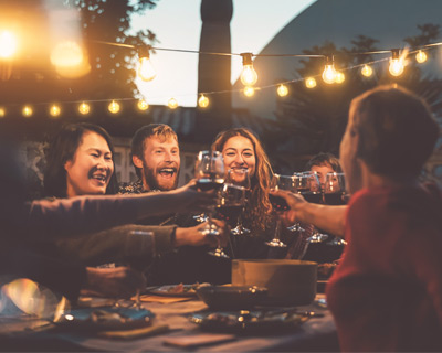 Freunde stoßen mit Rotwein an, Sommerabend-Idylle