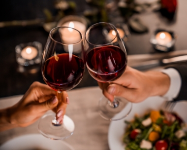 Zwei Rotwein-Gläser stoßen an, romantisches Dinner